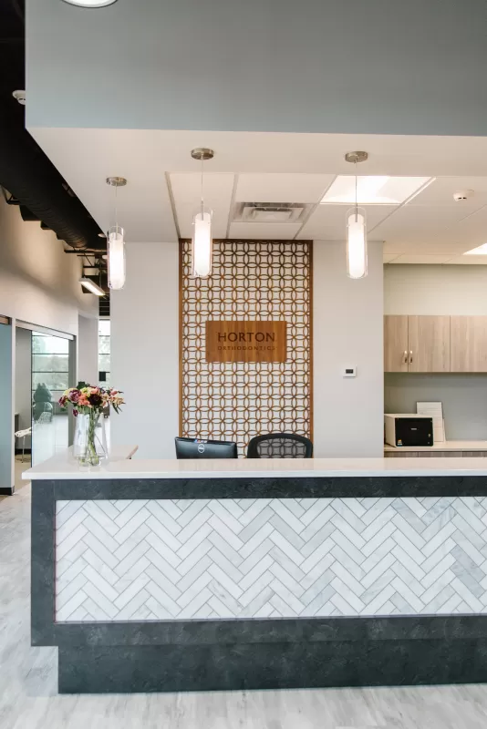 interior-impressions-horton-orthodontics-woodbury-mn-front-desk-grey-tile-wood-floor-white-wall-wood-design-wooden-sign-horton