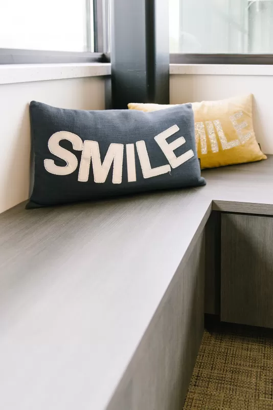 interior-impressions-horton-orthodontics-woodbury-mn-grey-bench-blue-and-yellow-smile-pillows-windows